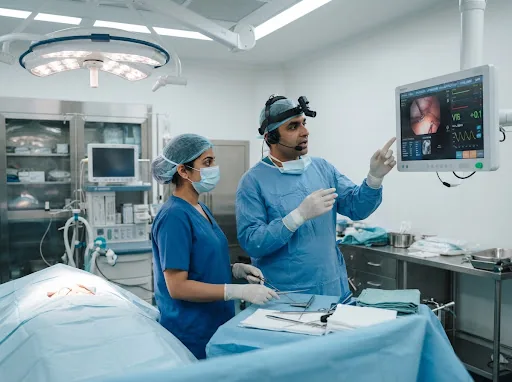 Modern Indian hospital operative ward: Indian male surgeon and surgical nurse using hands-free voice technology and wall display in operation theater